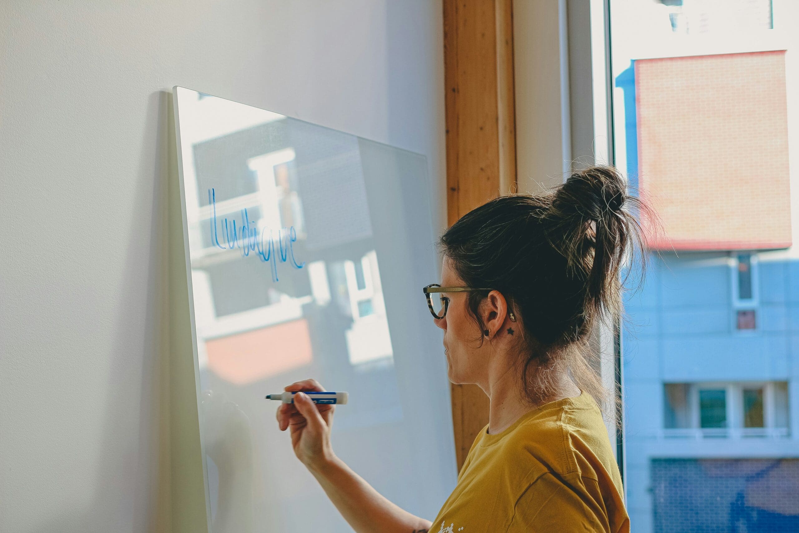 Service business owner writing on a whiteboard representing a founder with big ideas who can't scale because her operational infrastructure isn't in place