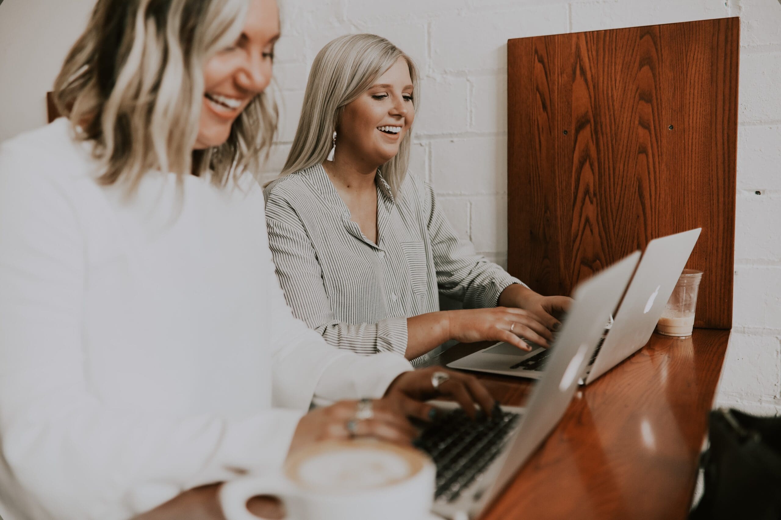 Two women collaborating on laptops representing a service business owner successfully delegating tasks to her team