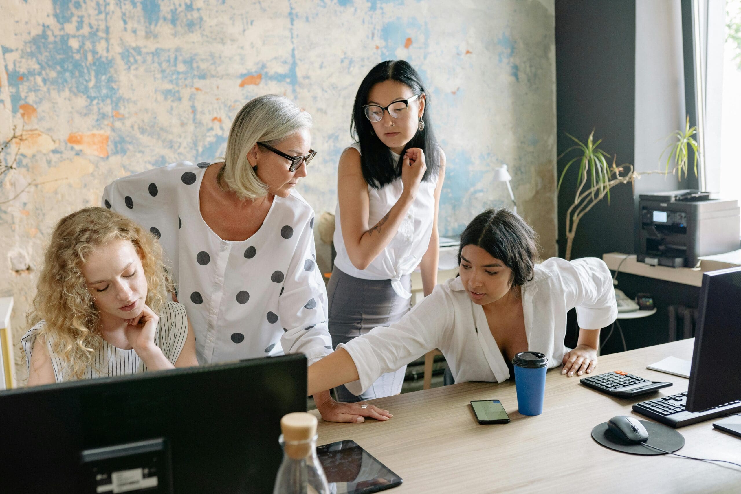 Service business owner standing over her team at a computer illustrating a founder whose business has outgrown its systems